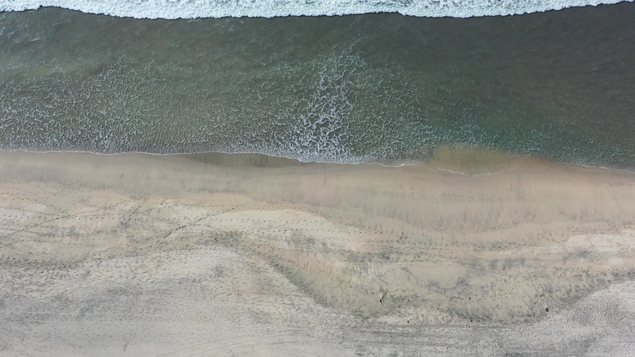 Overhead surf line with textured sand below.