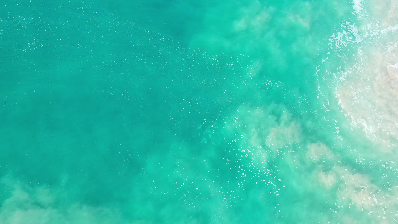 Turquoise ocean water with pale foam at the right edge.