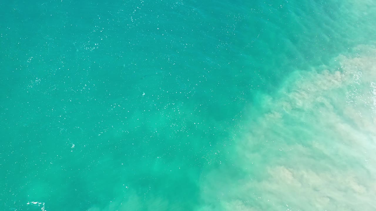 Shallow green-blue water with foamy white water on the right.