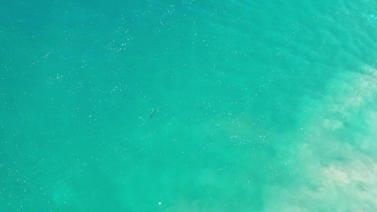 Blue green water with cloudy sand along the right edge.