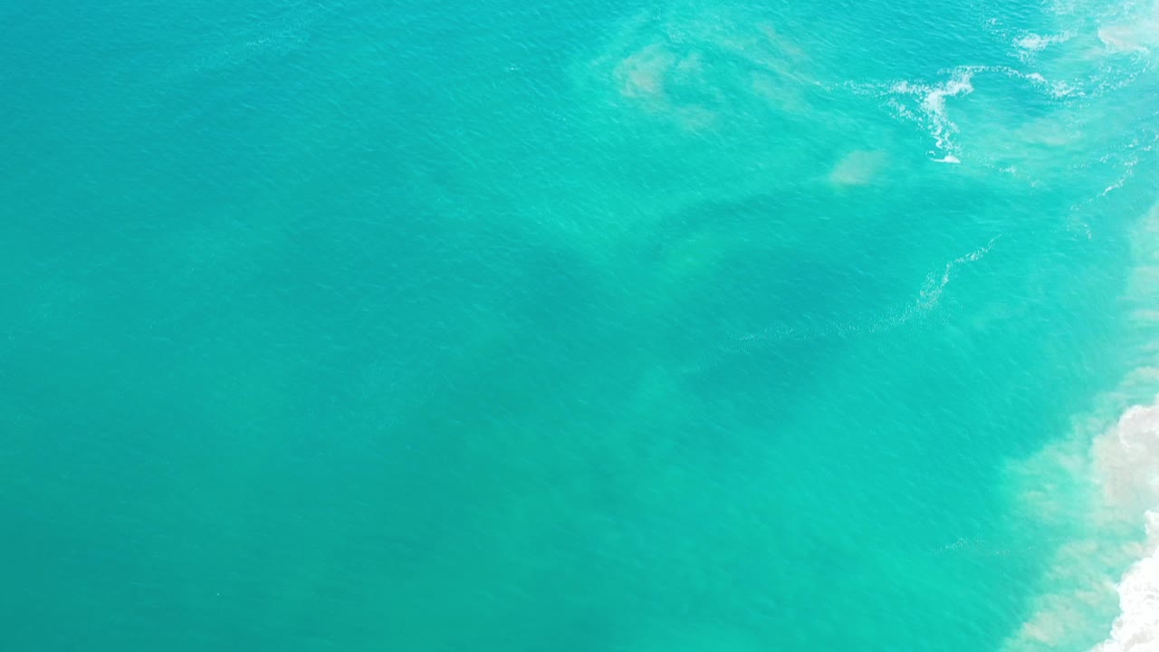 Turquoise ocean water with pale surf at the right edge.