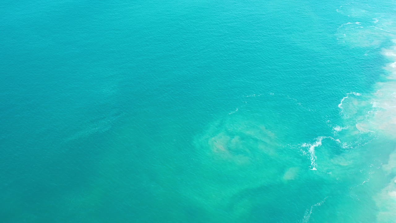 Turquoise ocean with pale surf at the right edge