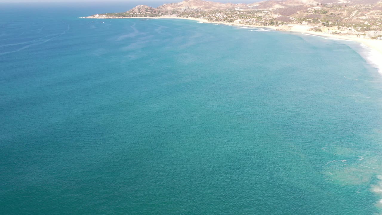 Aerial coastline with open water and distant hills.