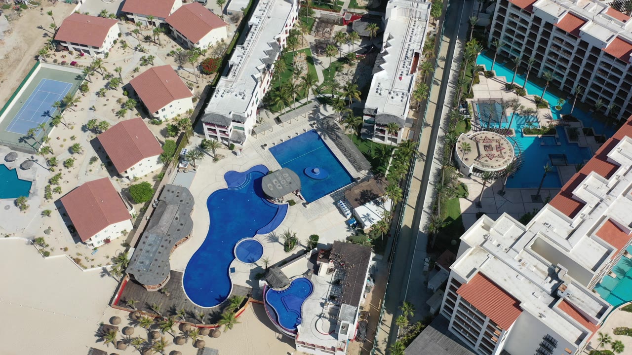 Resort pool area with tennis court and hotel courtyard from above.