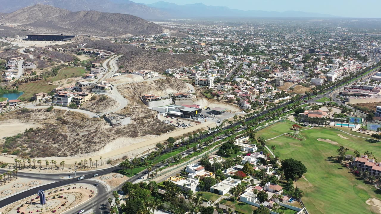 Drone view of hillside development beside homes and green space.