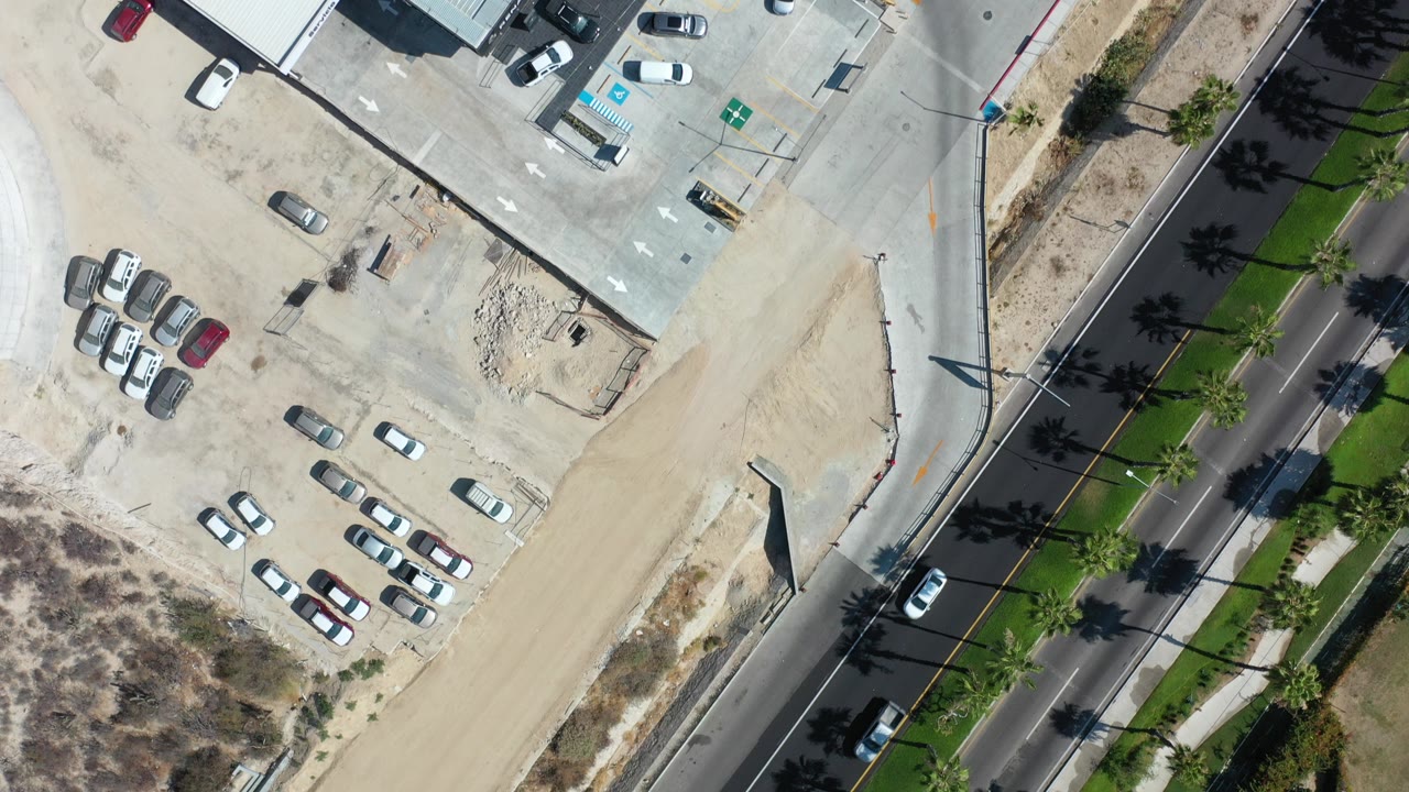 Overhead view of commercial rooftops, parking lots, and a palm-lined road.
