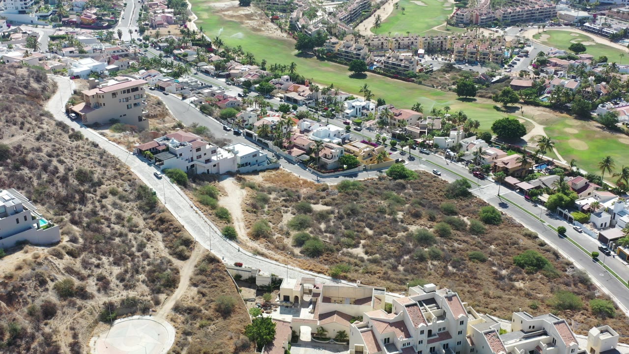 Aerial view of hillside roads, homes, and golf course greens.