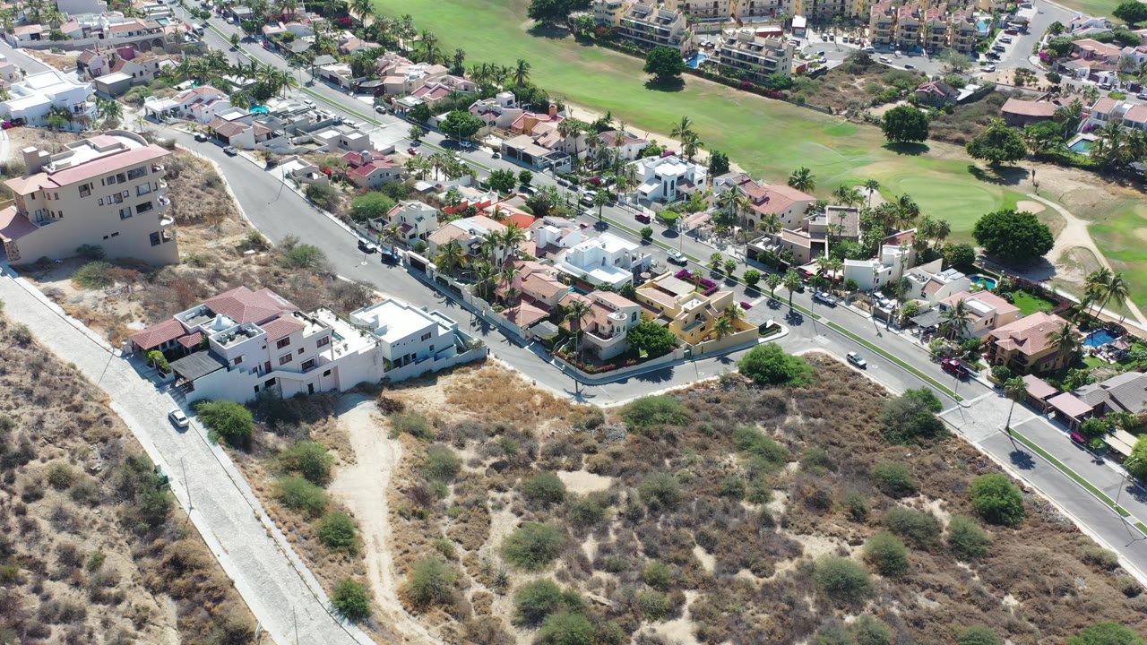 Aerial view of residential roads, dry scrub lots, homes, and green landscaping.