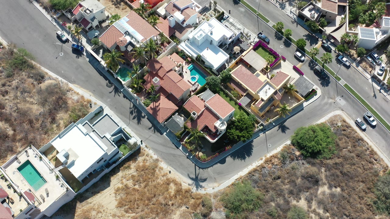 Overhead view of mansions, pools, roads, and dry lots.