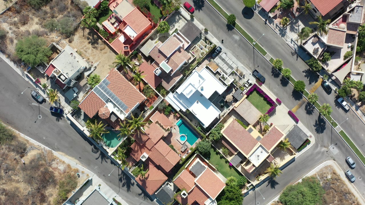 Overhead view of modern homes, roads, pools, and dry lots.