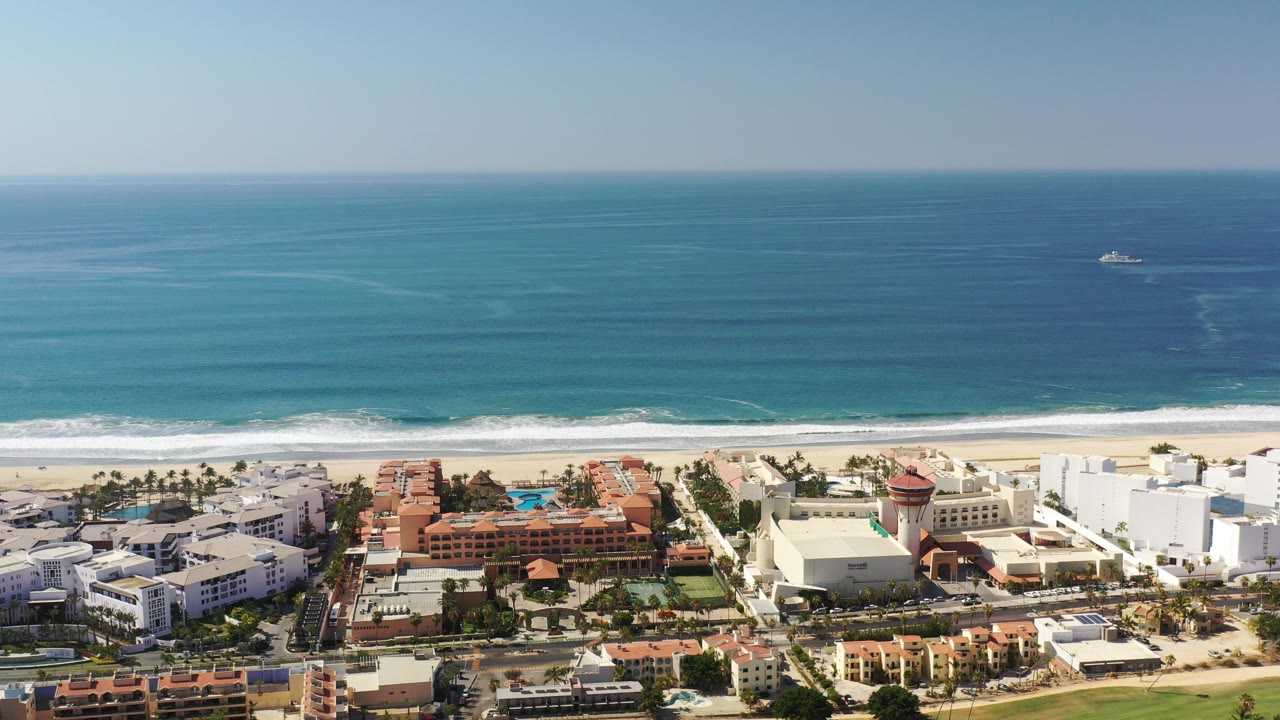 Aerial view of turquoise ocean, beach, and coastal buildings.