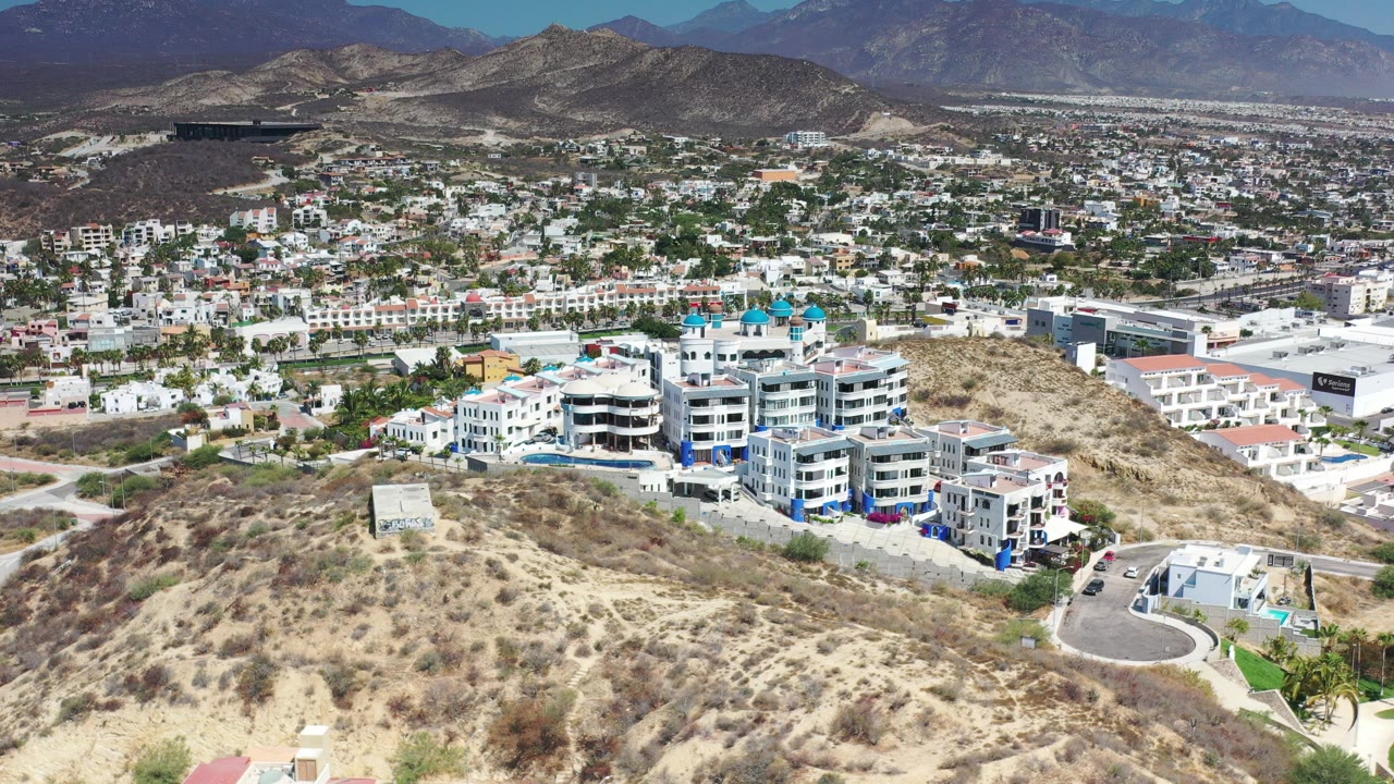 Aerial view of modern buildings beside scrub-covered hills and a townscape