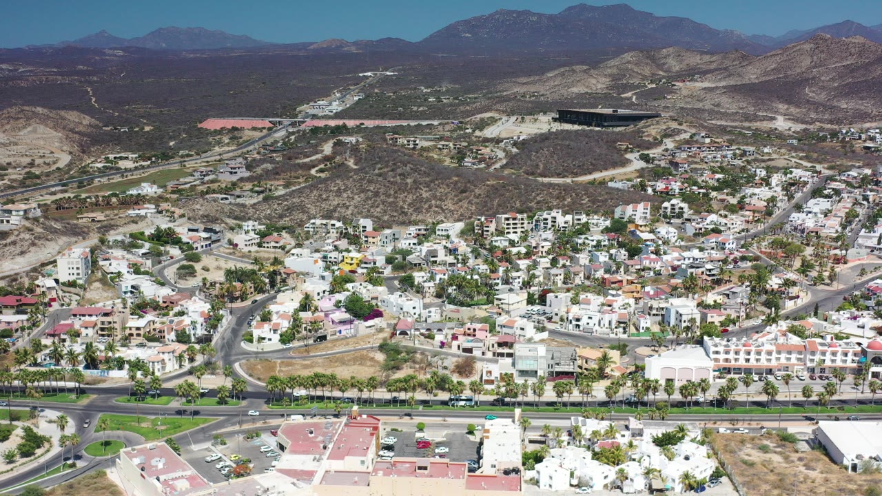 Aerial view of hillside homes, roads, cars, and mountains.