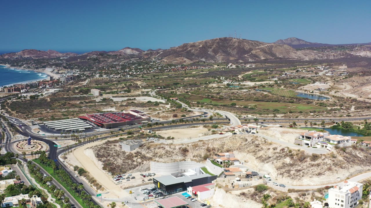 Aerial view of coastline, roads, fields, buildings, and mountains.