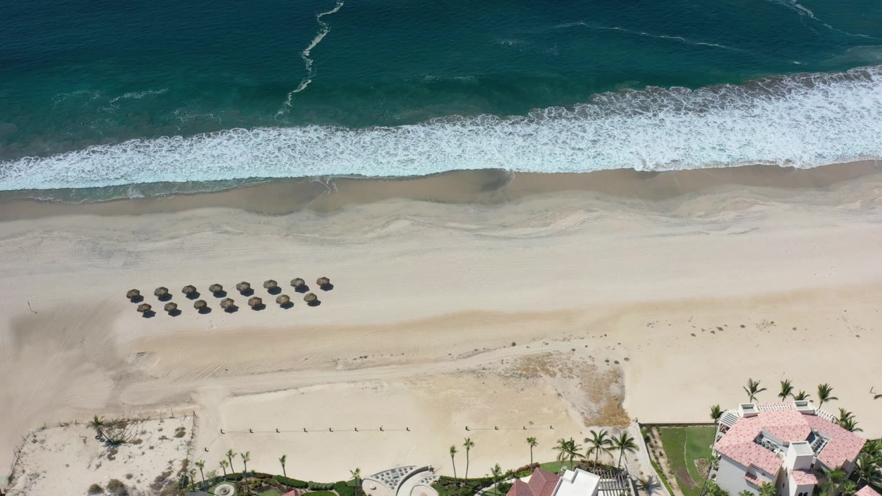 Wide overhead surf and beach with homes along the bottom edge