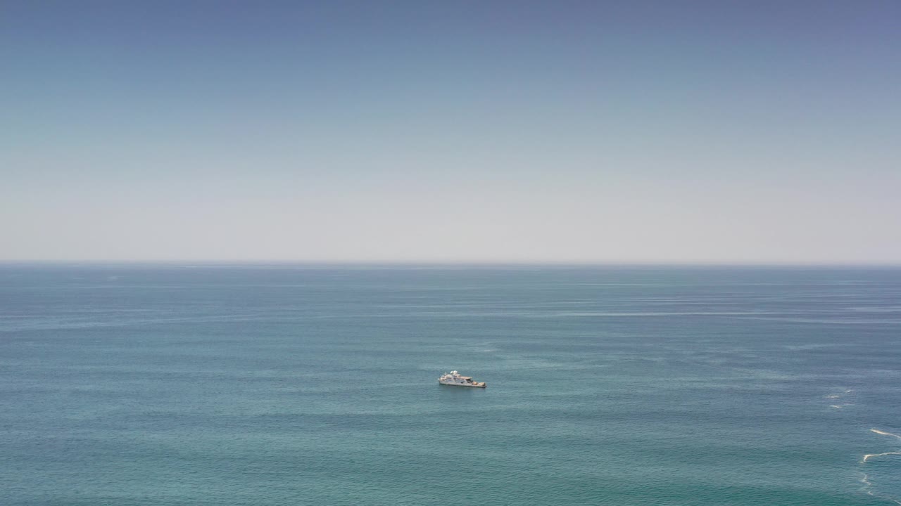 Small offshore boat under clear sky on green sea.