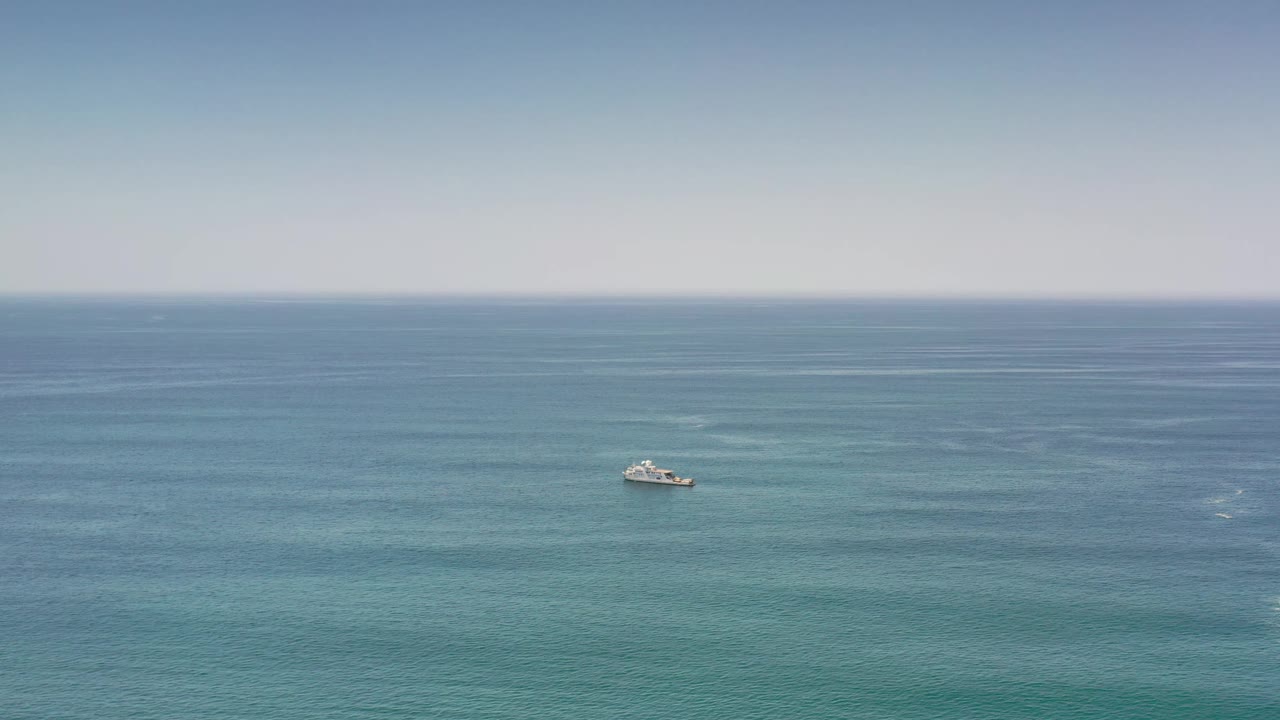 The boat remains small in the left midground on the Los Cabos ocean, with subtle water texture and no visible people.