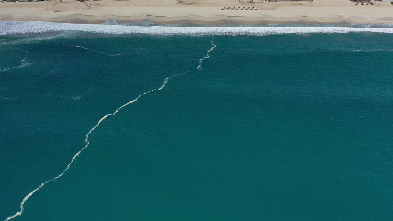 Aerial view of teal ocean beside a sandy beach