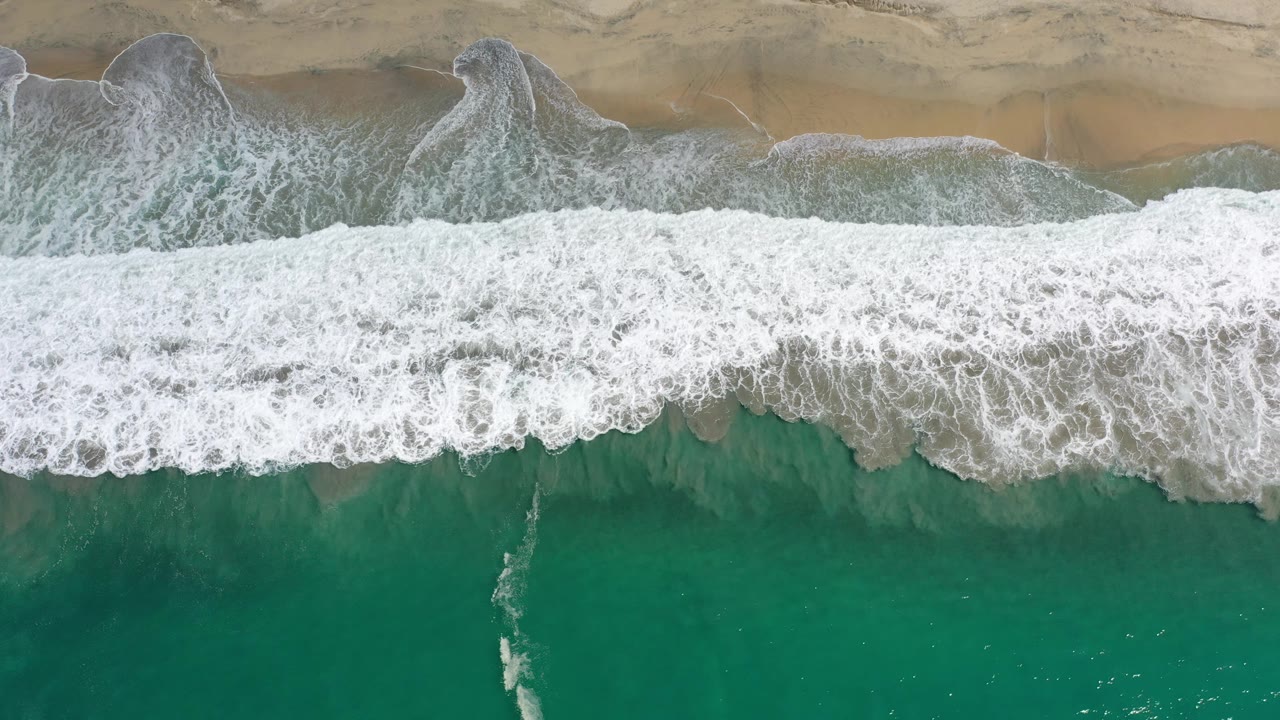 Aerial wave foam reaching across the shoreline