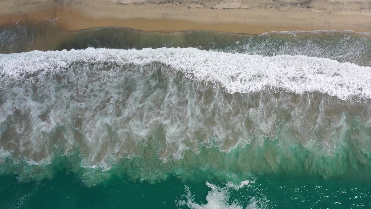 Aerial view of white surf and green water.