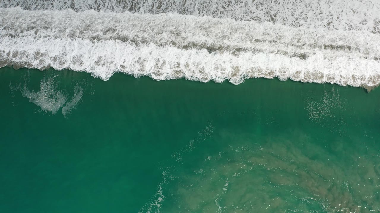 Aerial view of a breaking wave and darker water below.