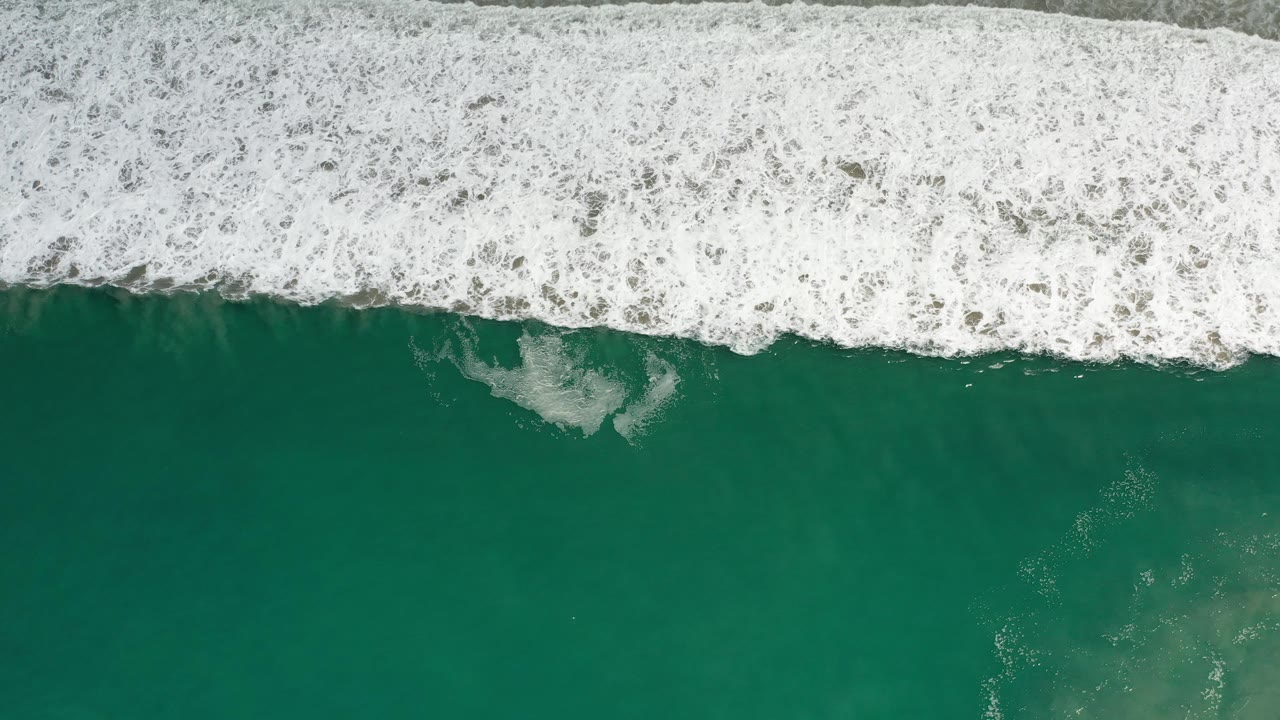 Green sea water beneath a wide white surf line.