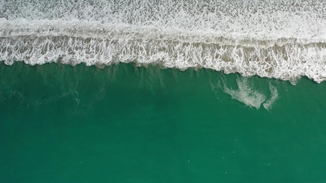 Top-down view of breaking wave foam and open green water
