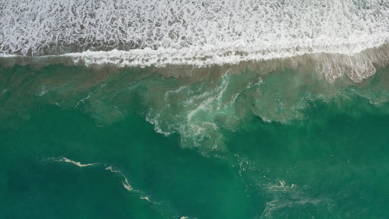 Foamy surf line above open teal water.