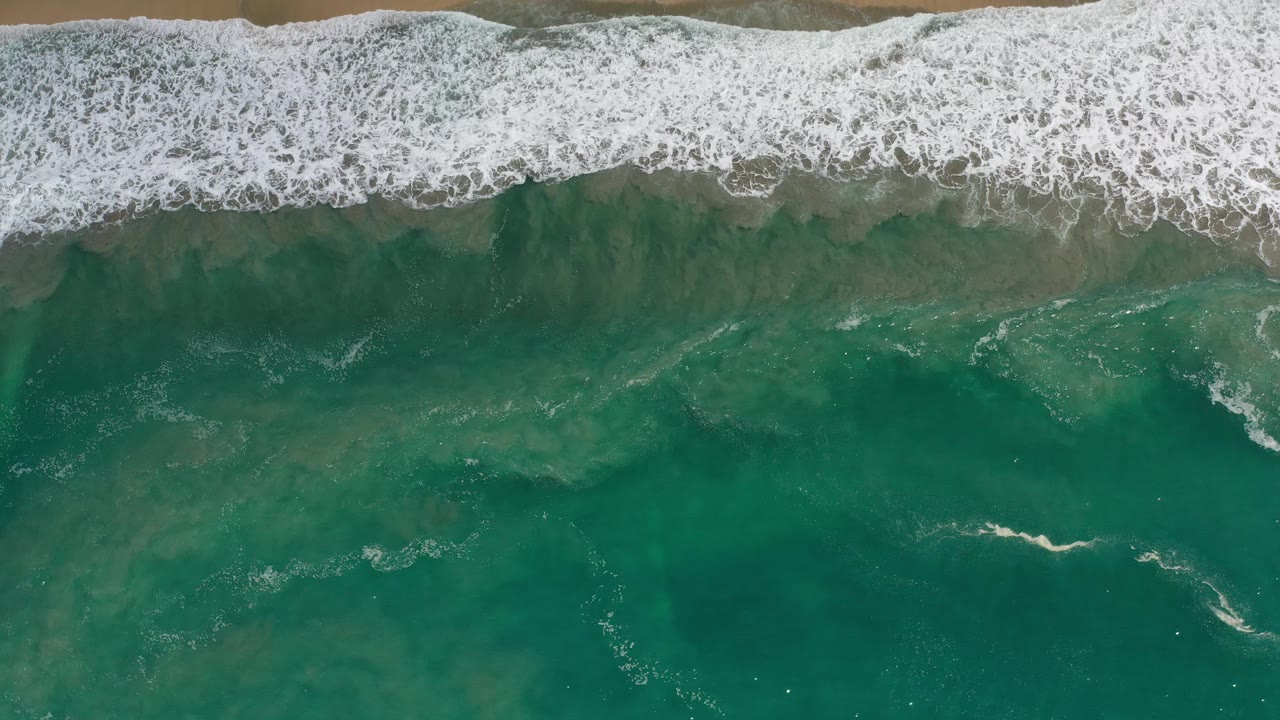 Foam band curling over darker green sea