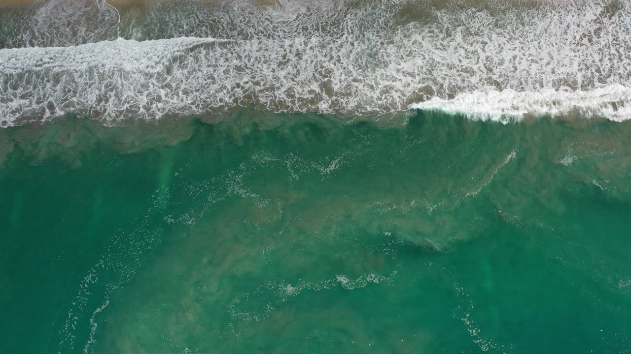 Overhead surf washing onto a sandy shoreline