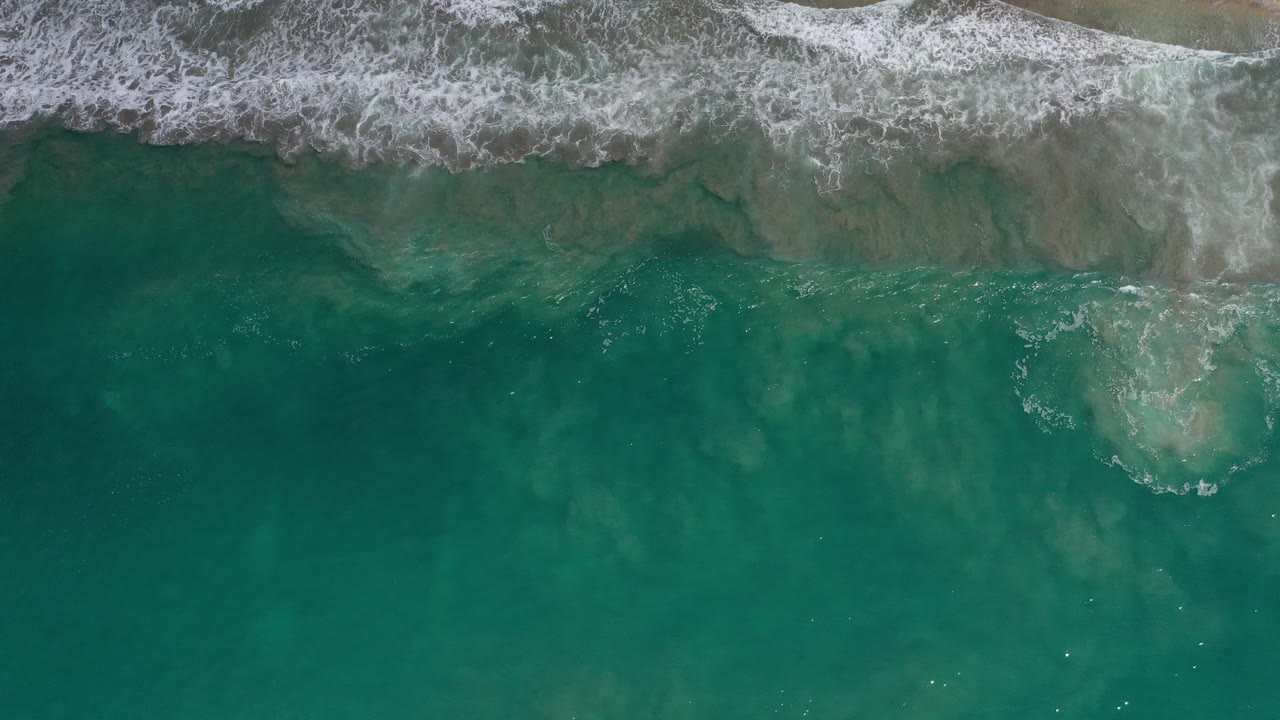 Overhead green ocean water with white surf foam near the top edge.