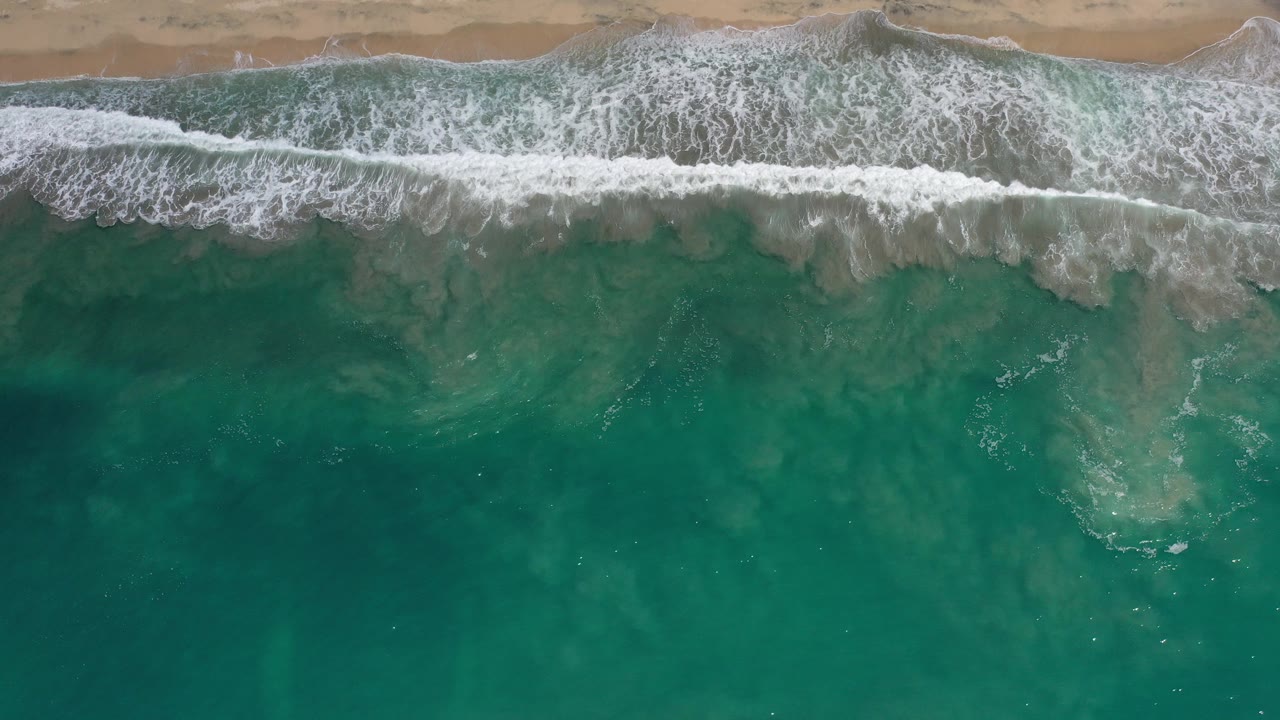 Overhead surf breaking onto a sandy beach