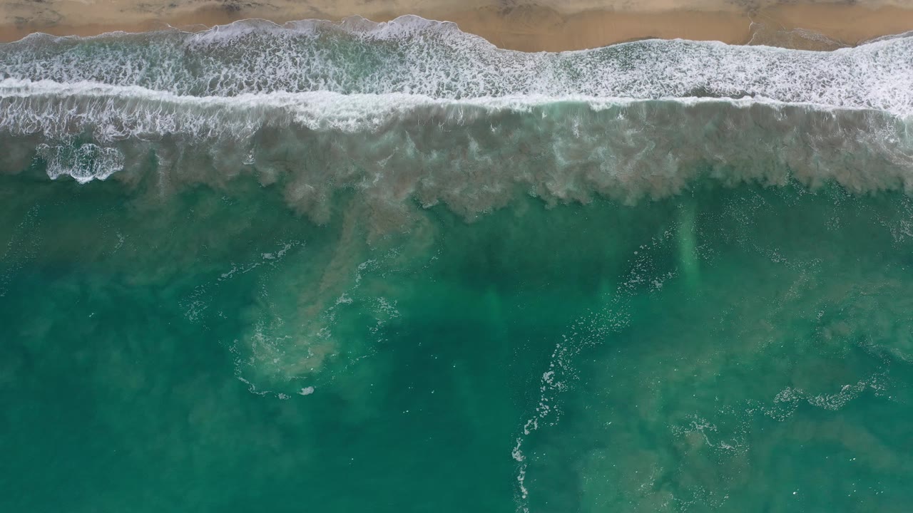 Aerial shoreline with foamy waves and open water