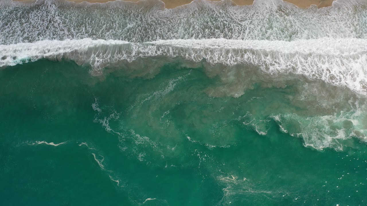 Foamy surf breaks along the top of a teal ocean frame.