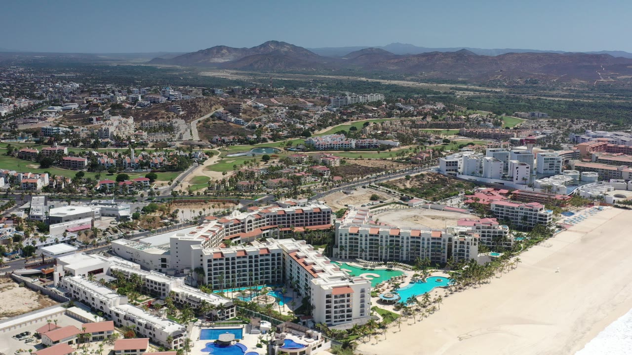 Aerial view of beachside apartment buildings, pools, roads, hills, and mountains