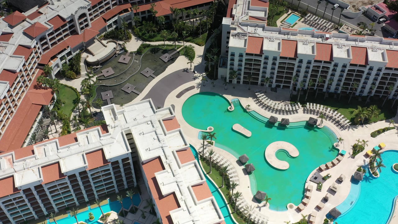 Overhead resort courtyard with pool, chairs, and hotel balconies.