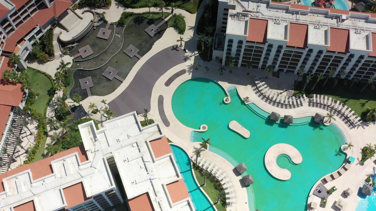 Overhead resort pools beside white buildings and lounge chairs