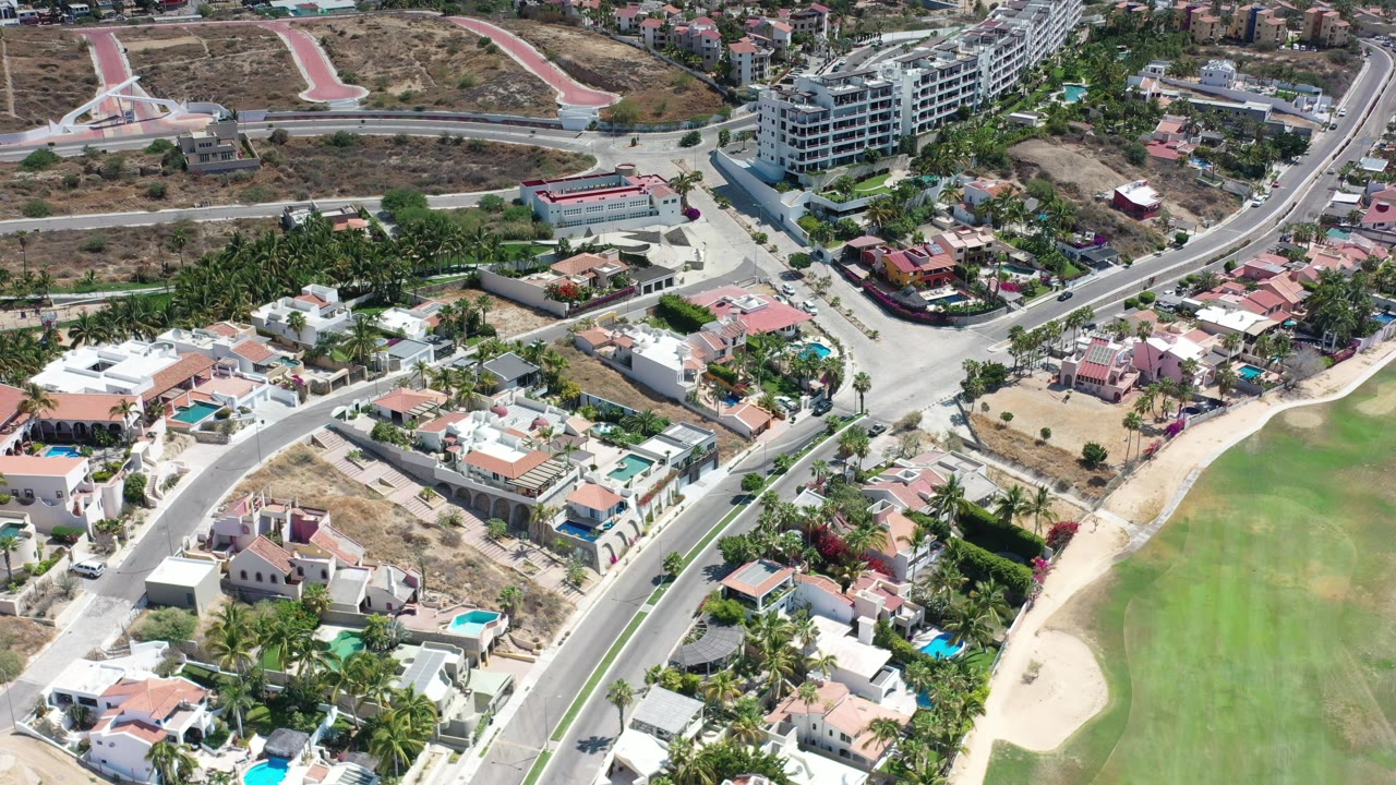 Aerial view of homes, roads, palms, and a golf fairway edge.