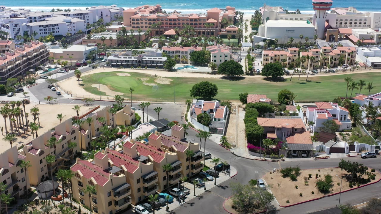 Aerial view over resort buildings, roads, golf green, and ocean