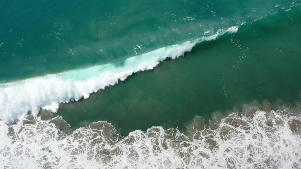 Large white surf line over shallow rocks.