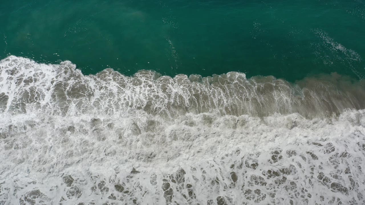 White surf curling across blue-green ocean water