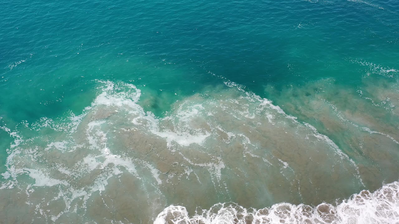 Blue ocean and foamy surf lines seen from above.