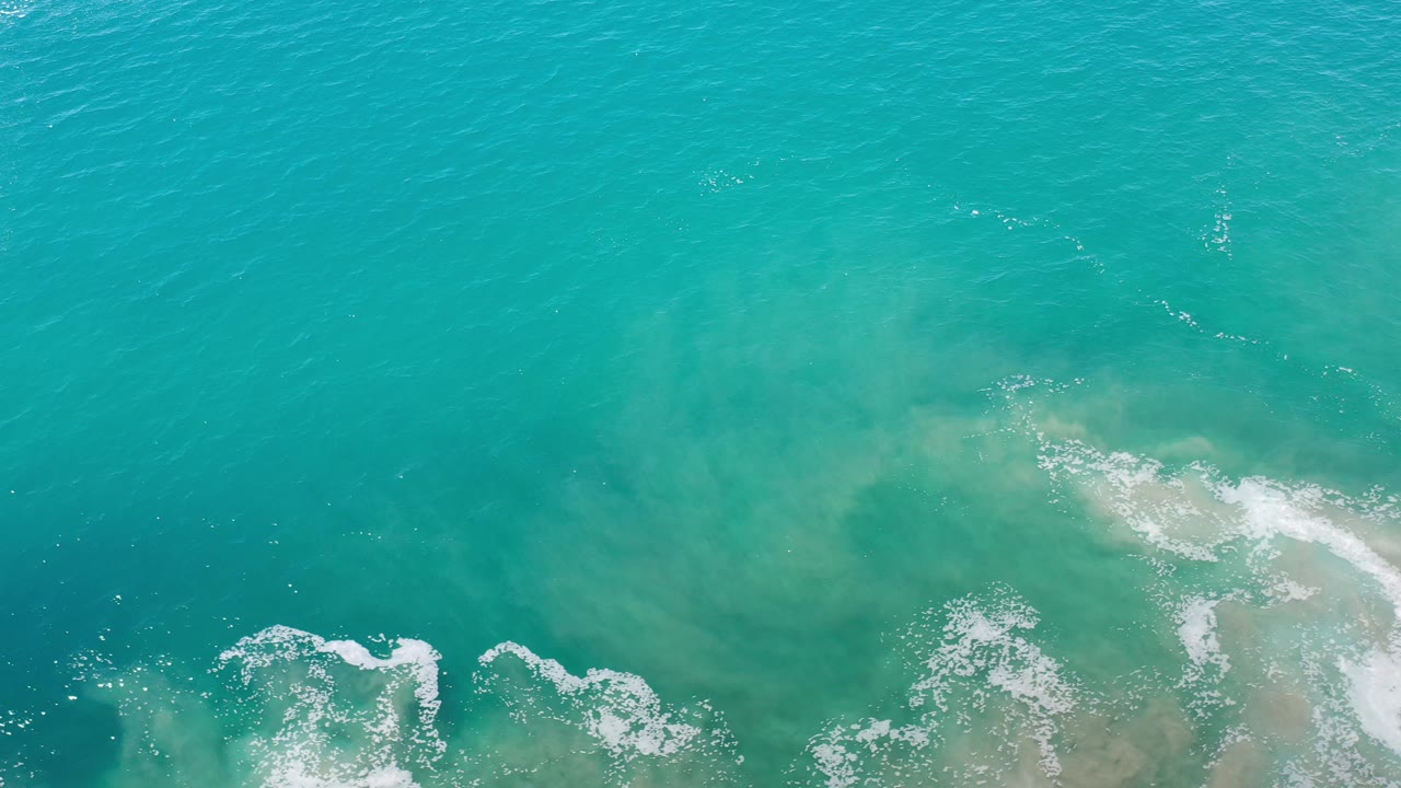 Turquoise sea with curved foam streaks and faint underwater color.