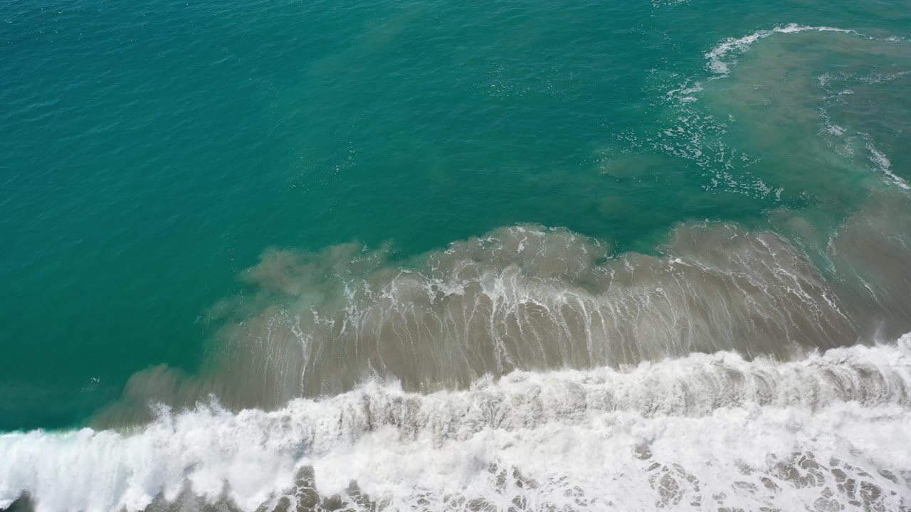 Foamy surf thickens along the lower edge of the aerial frame.