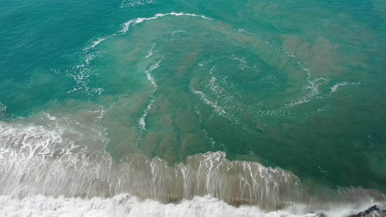 Aqua ocean with white surf pushing across the beach edge.