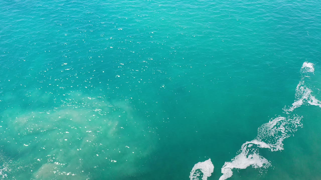 Blue-green ocean surface with foam curl near the lower right.
