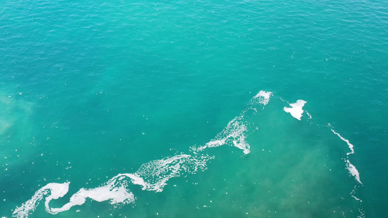 White foam breaks into separate patches on turquoise water.