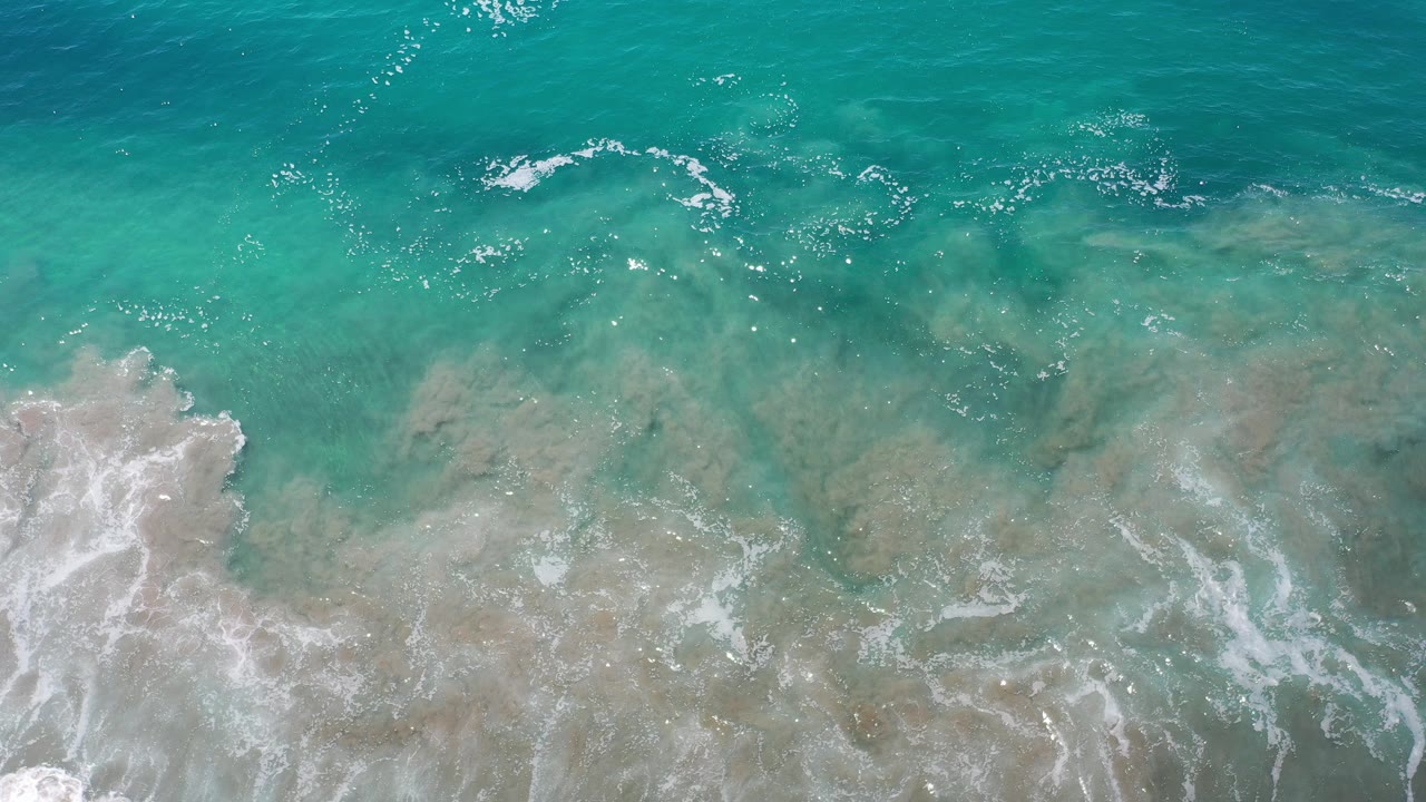 Overhead turquoise surf rolling onto sandy shallows