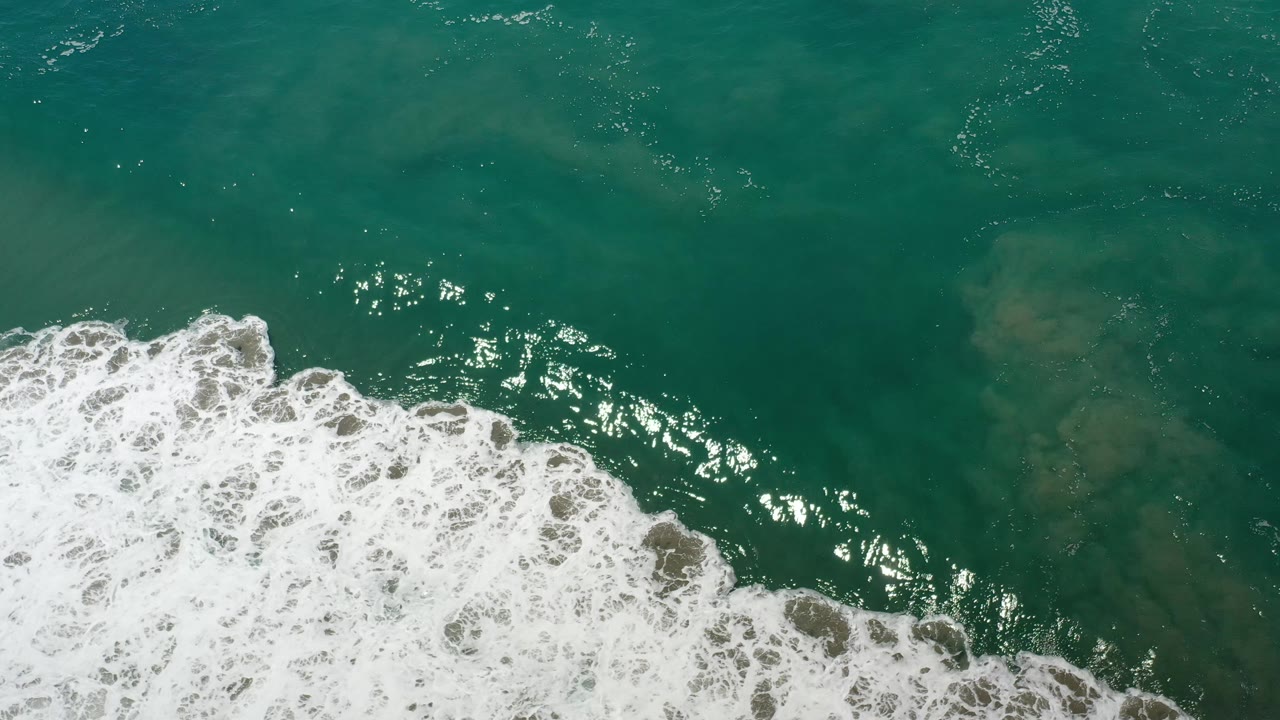Foamy small waves run along the lower half of green seawater.