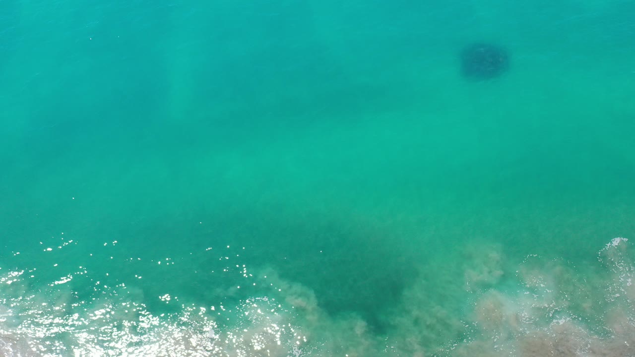 Overhead turquoise ocean with white surf foam at the bottom edge.